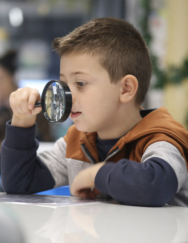 St Luke's Catholic School Marsden Park Early Learning Centre student looking through magnifying glass